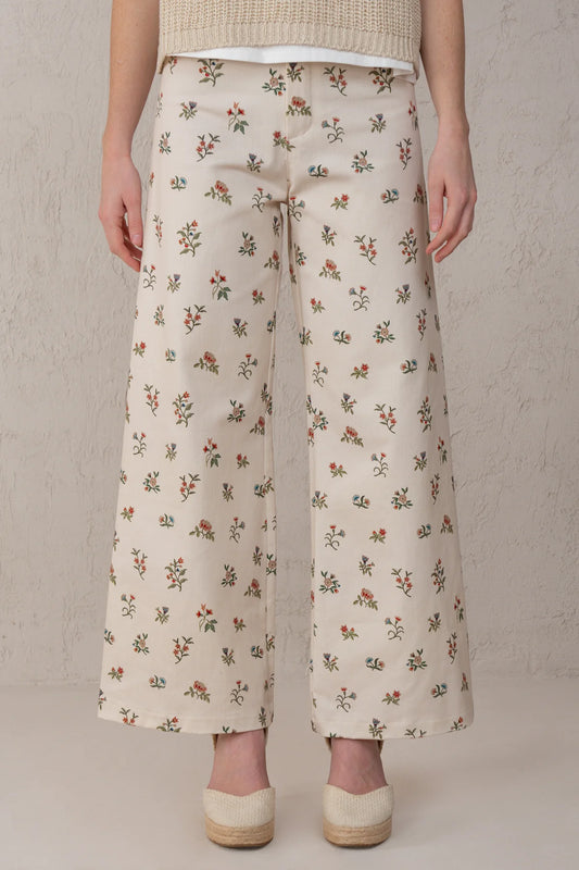 Person wearing floral-patterned pants against a neutral background