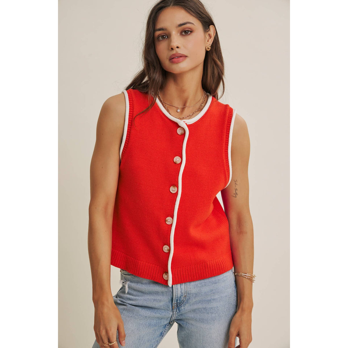 Woman wearing a red cardigan with white trim against a neutral background