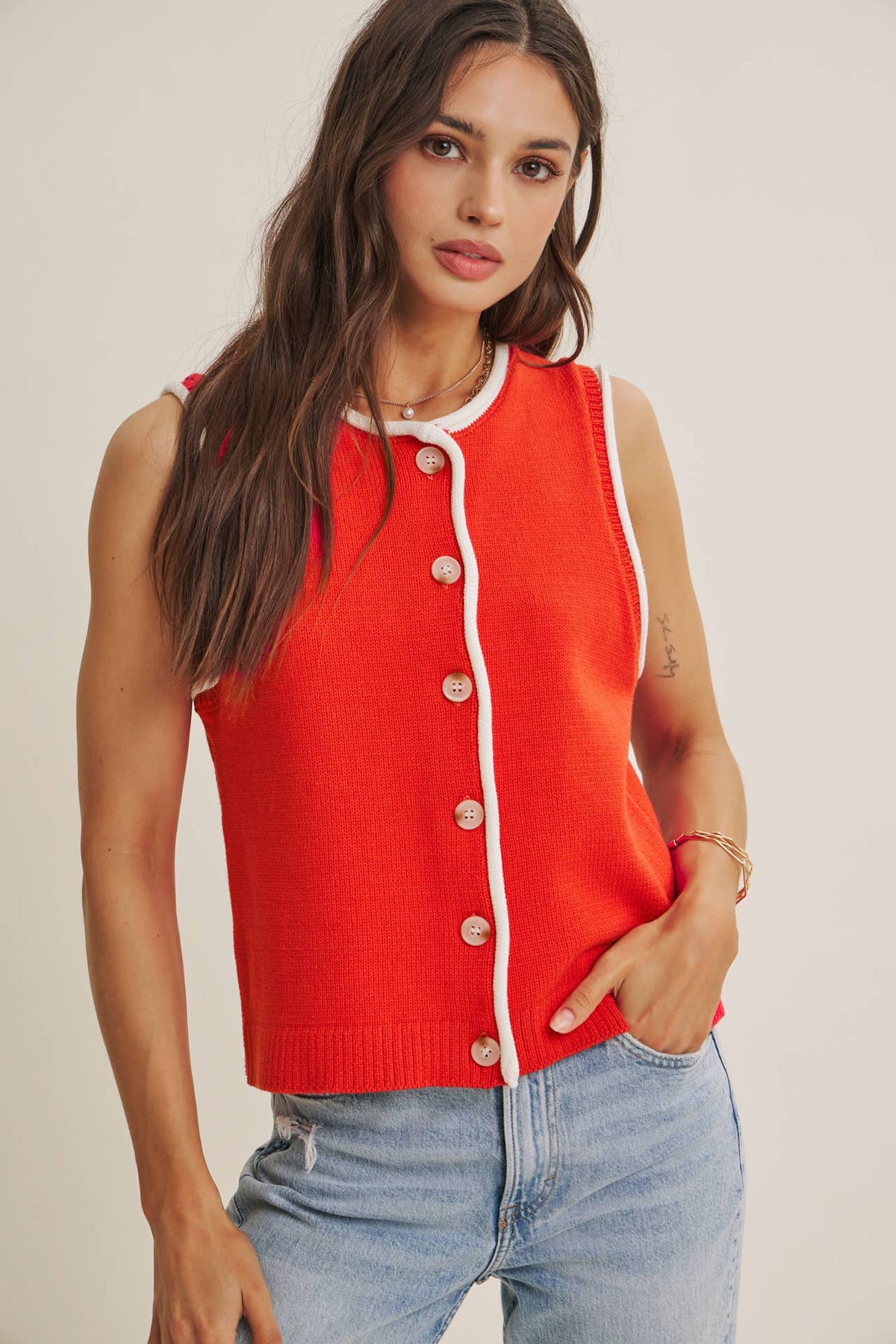 Woman wearing a red cardigan with white trim against a plain background