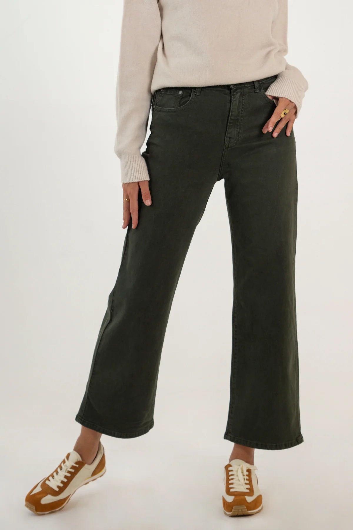 Person wearing black wide-leg jeans and brown shoes on a white background