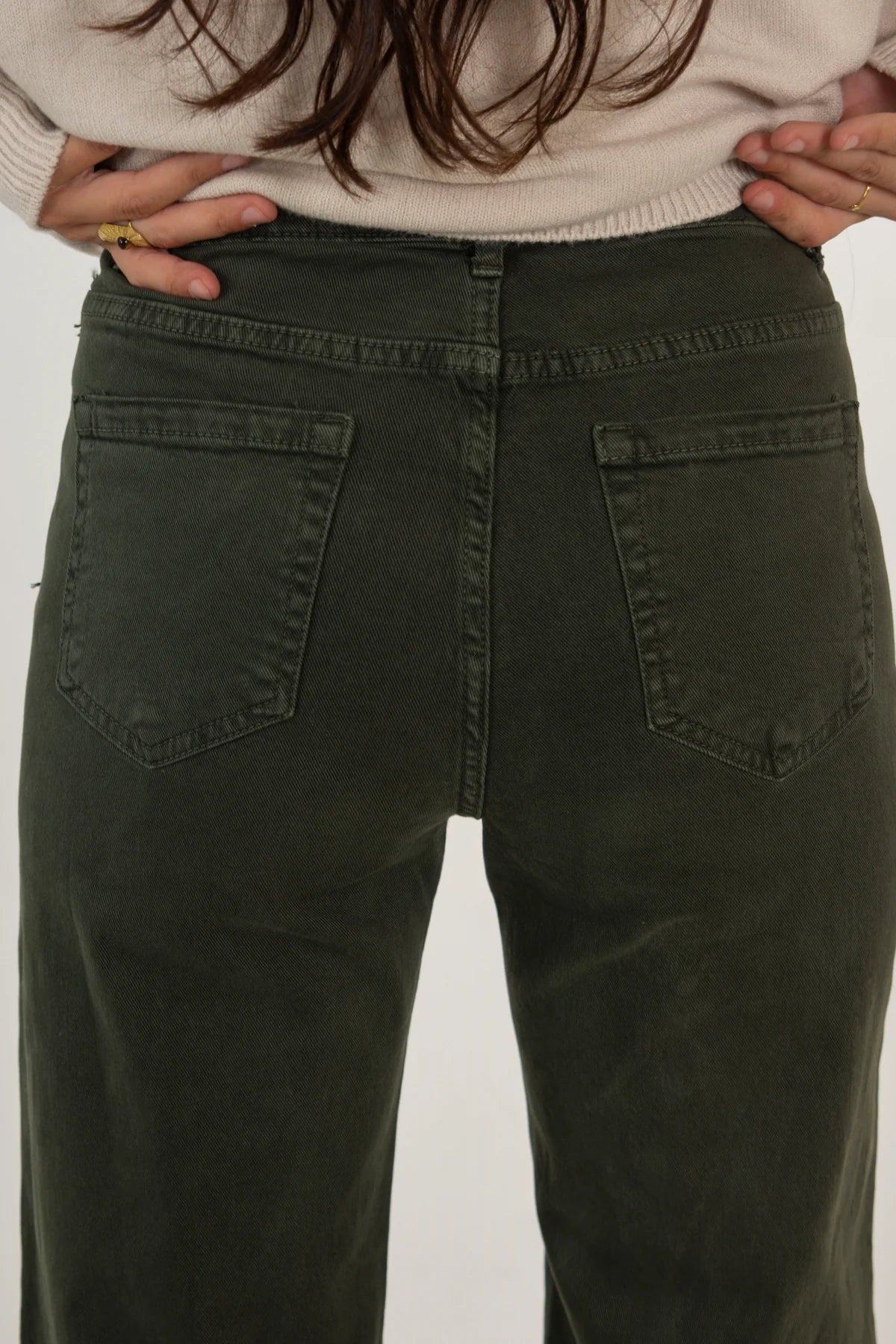 Person wearing olive green pants with a plain background