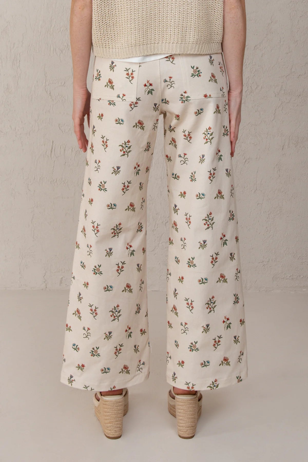 Person wearing floral-patterned pants on a plain background