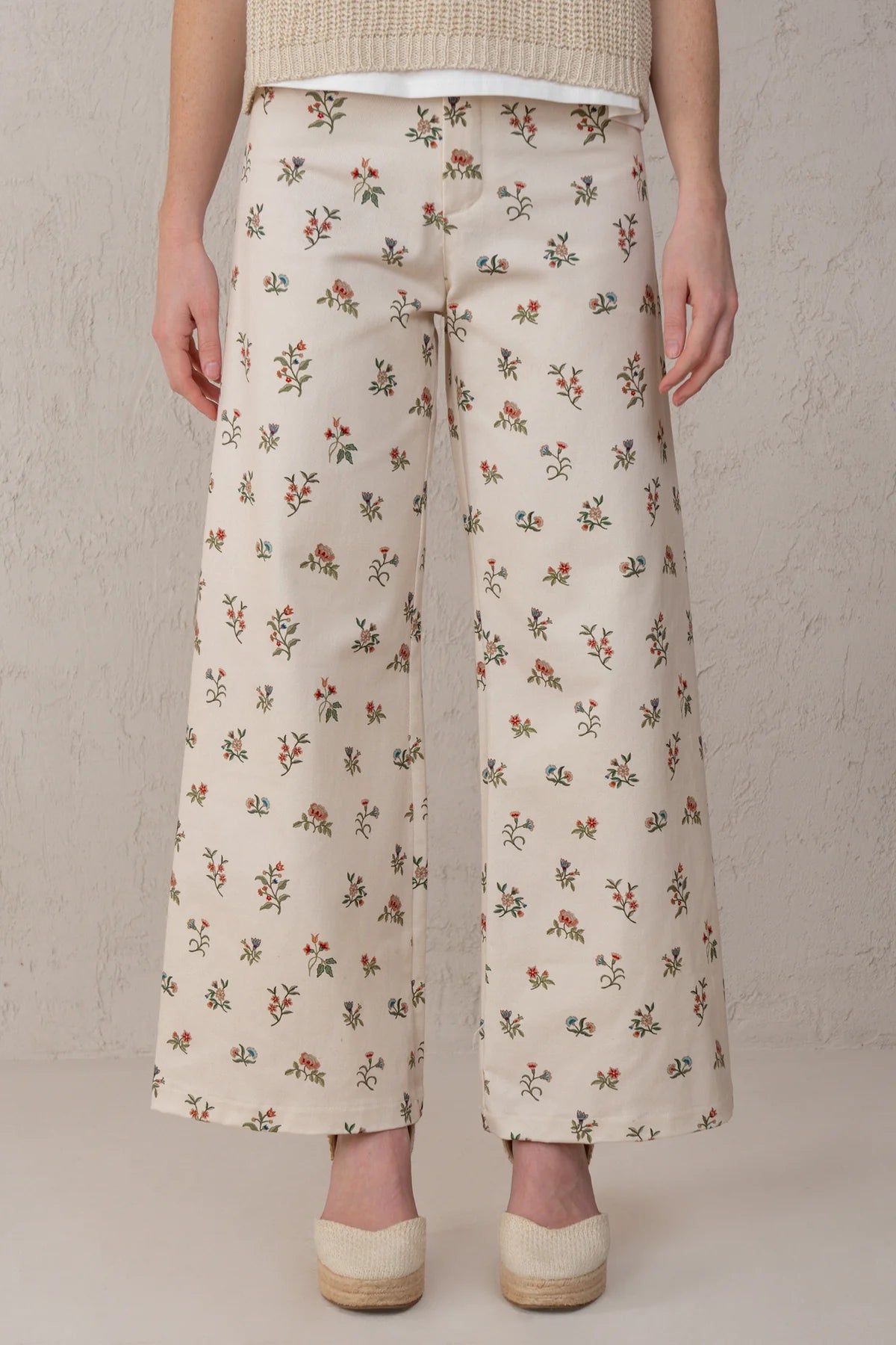 Person wearing floral-patterned pants against a neutral background