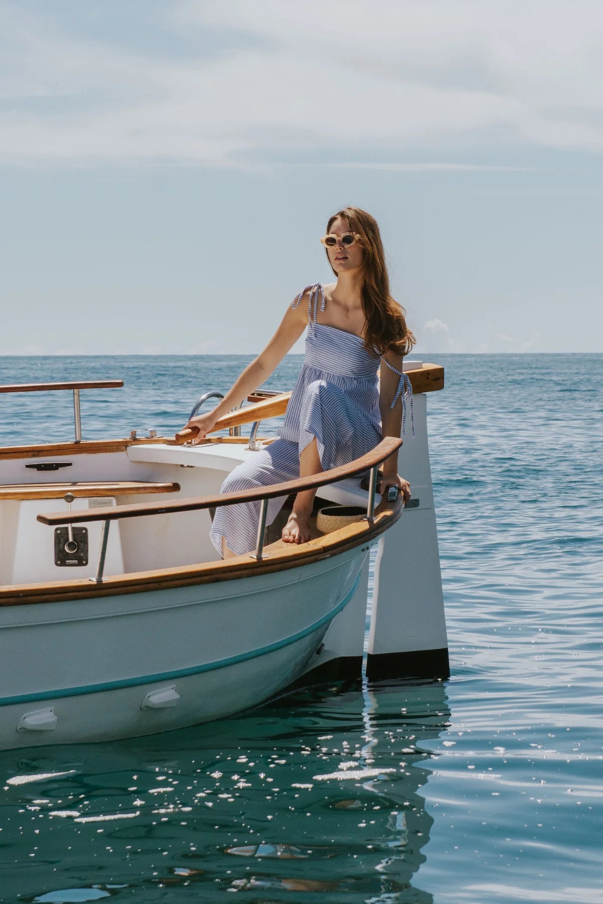 Woman sitting on a boat in the ocean with a clear sky.