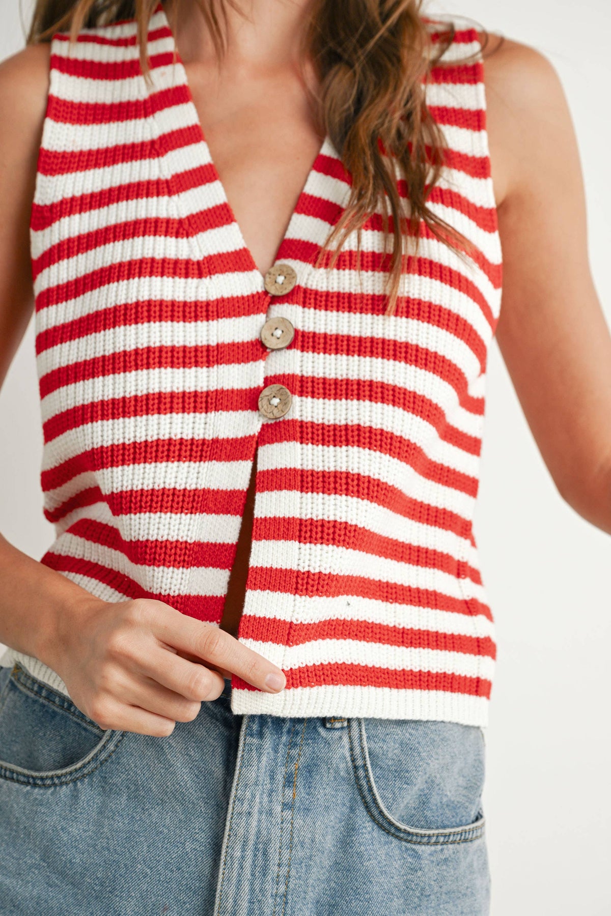 Red and white striped sleeveless top worn by a person on a plain background