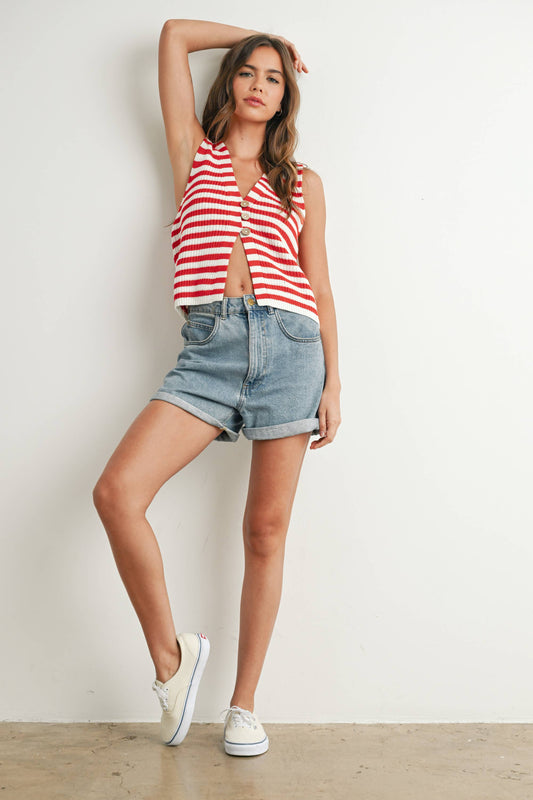 Woman wearing a red and white striped tank top and denim shorts against a plain background