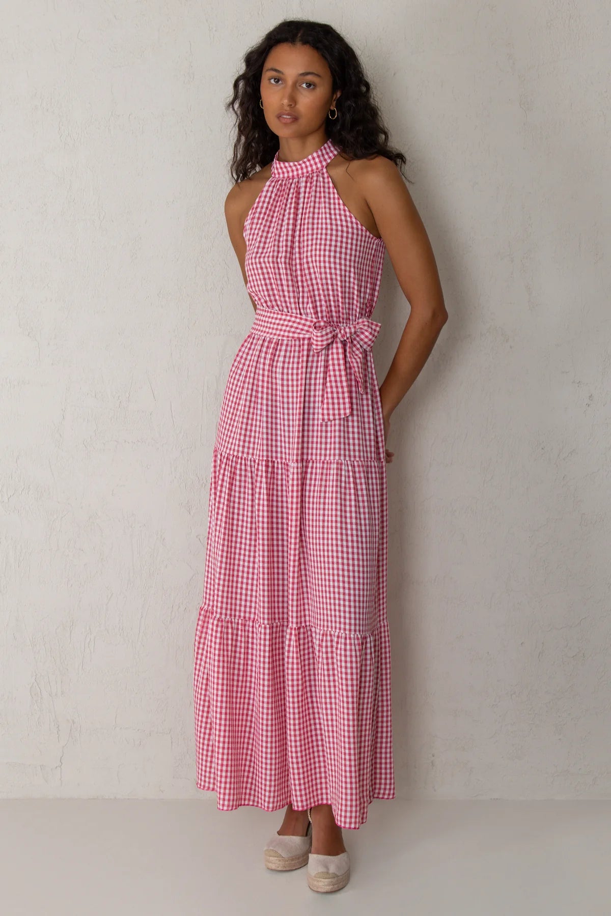 Woman wearing a red and white checkered dress against a plain background
