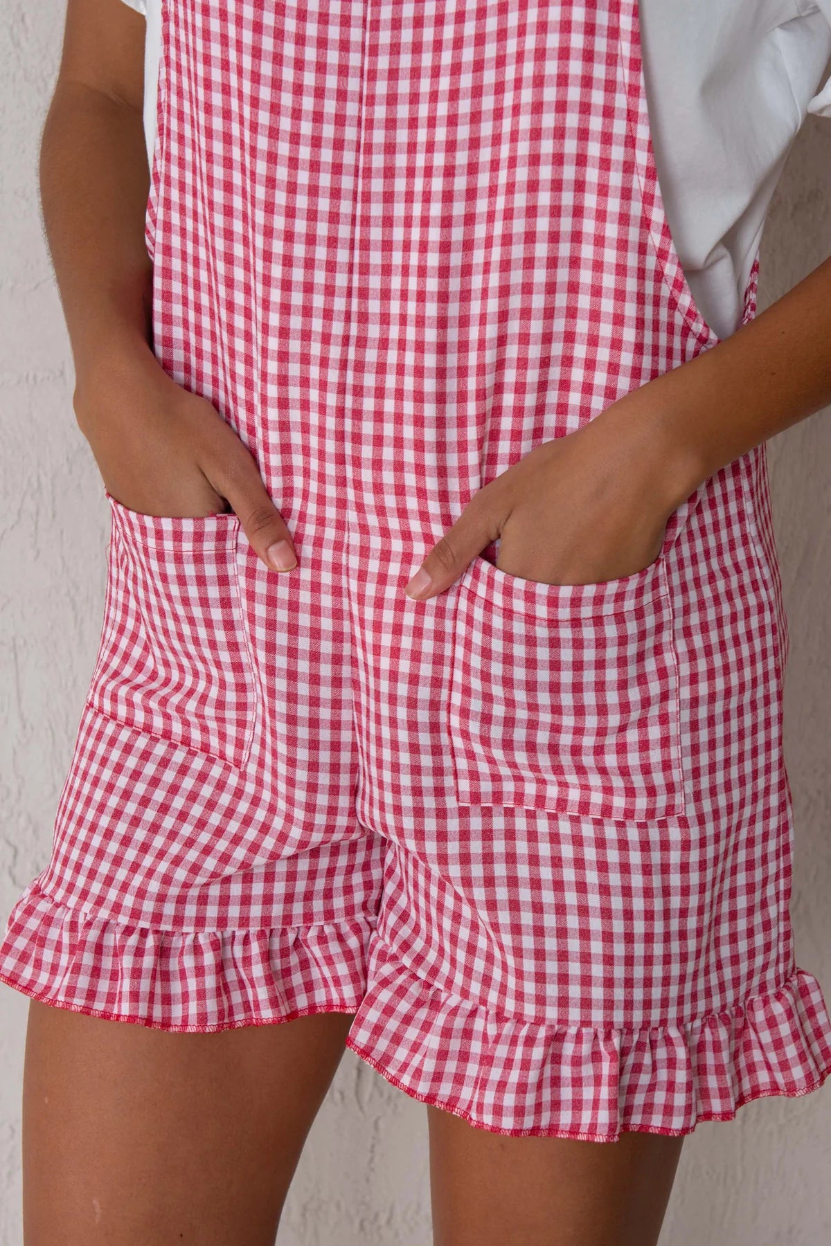 Red and white checkered romper with ruffled shorts on a plain background