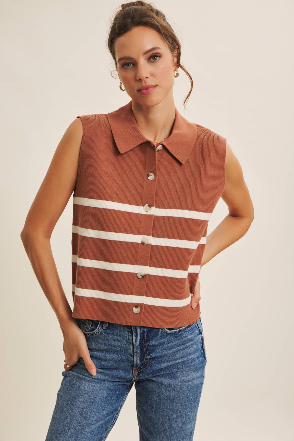 Woman wearing a sleeveless striped shirt with a plain background
