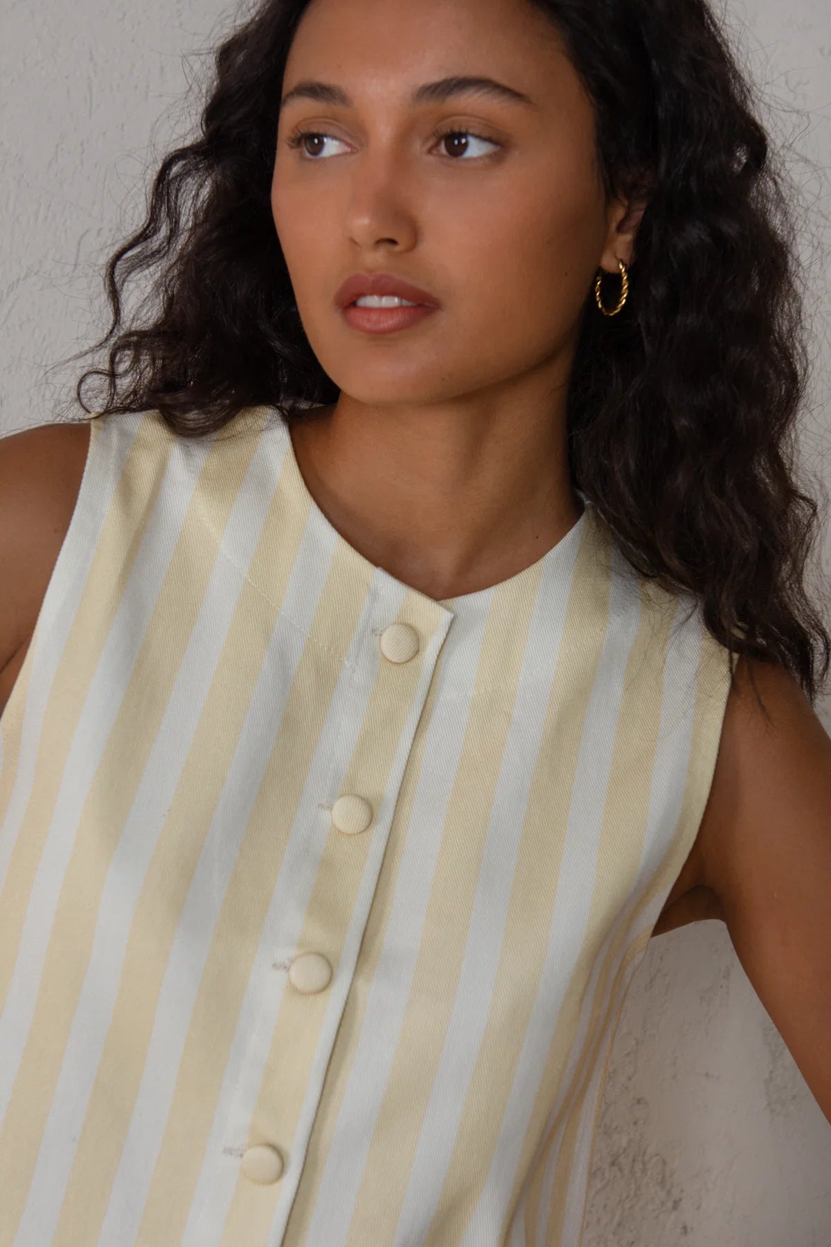 Woman wearing a sleeveless striped dress with a neutral background